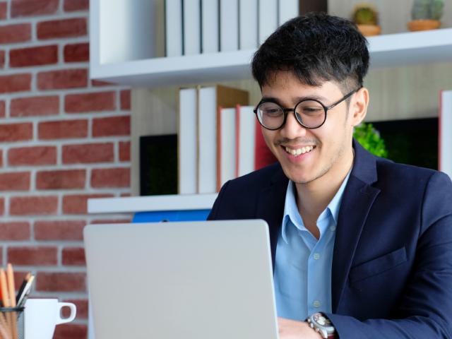 Young happy asian businessman working with laptop computer at office background