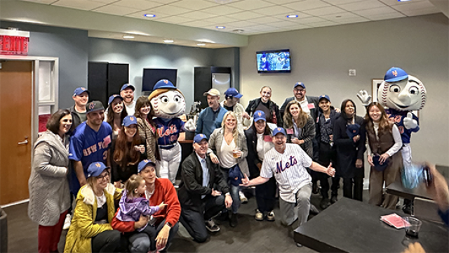 Group of people posing for a photo with Mr. and Mrs. Met