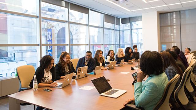 Diverse colleagues sitting at a boardroom table engaged in a discussion