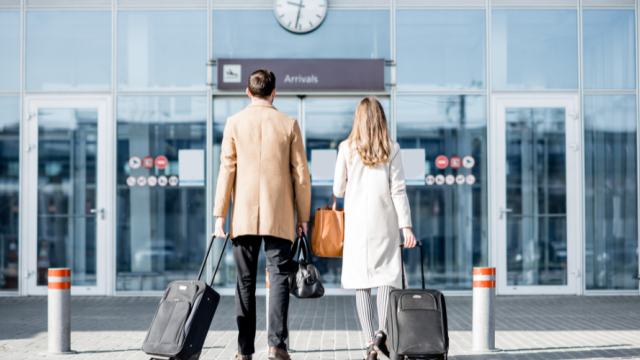 Man and woman walking into airport with suitcases