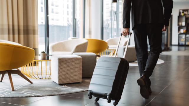 Man walking through hotel lobby with his wheelie suitcase