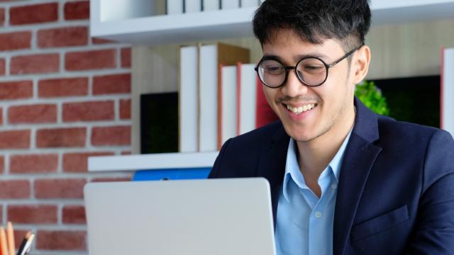 Young happy asian businessman working with laptop computer at office background