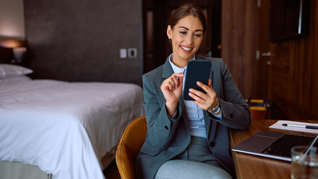 A woman sitting on a chair in her hotel room representing how travellers get an extra layer of traveller security with Safe & Secure. 