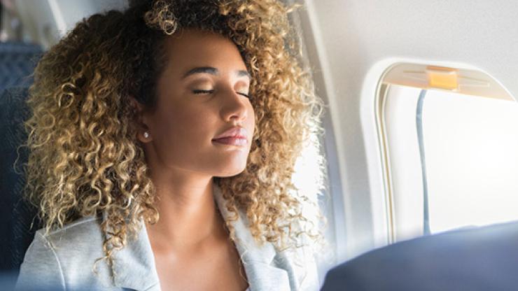 Relaxed business traveler sitting in a plane seat with eyes closed