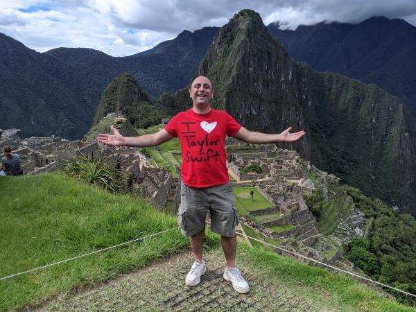 Man standing infront of Machu Picchu wearing an I love Taylor Swift red shirt