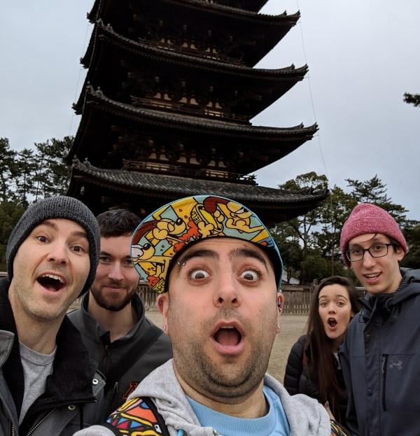 group of friends standing in front of a temple with surprised faces