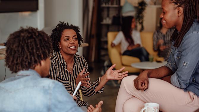 three black professionals sitting in an office talking