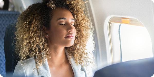 Relaxed business traveler sitting in a plane seat with eyes closed