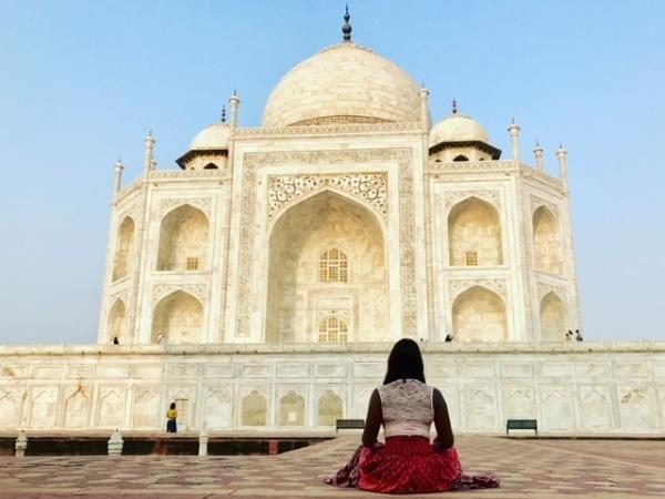 woman sitting on ground in front of landmark in india