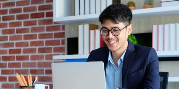 Young happy asian businessman working with laptop computer at office background