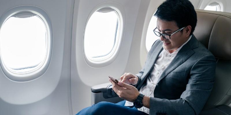 Asian male traveller on his phone on an airplane