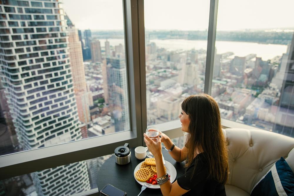 a woman eating breakfast by a hotel room window