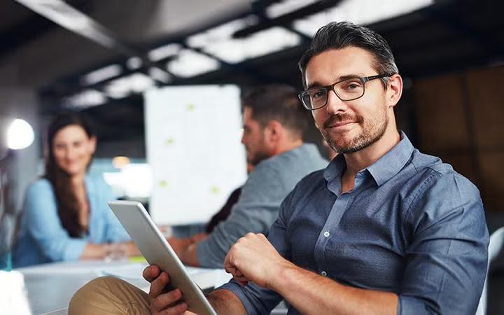 Man holding a tablet in the office how to leverage corporate travel discounts to maximise your savings.