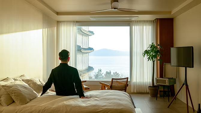 A man sitting on a hotel bed, reflecting the experience of Aussies travelling for work and work-related travel.