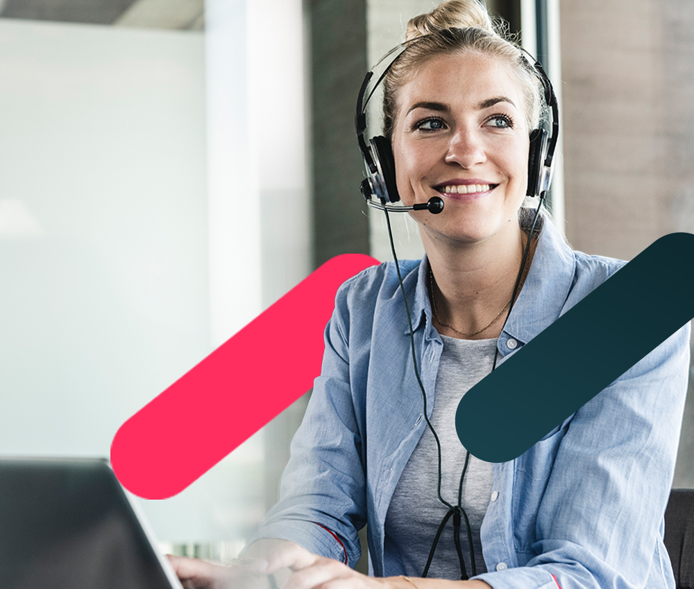 Customer support agent with headset typing on laptop in modern office